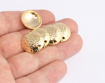 May include: A collection of gold-colored, hammered-texture metal jewelry components. The components are round with a slightly domed shape and small holes for attaching to other pieces. One component is smooth, while the others have a textured surface.