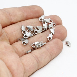 Pu&ograve; includere: Una collezione di piccole chiusure a moschettone in metallo color argento, ciascuna dotata di un meccanismo a molla e di un piccolo anello a un'estremit&agrave; per il fissaggio. Questi componenti per gioielli servono per fissare collane e bracciali.