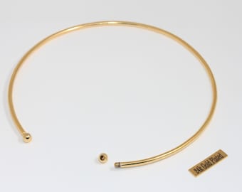 May include: A gold-colored choker necklace with a simple, elegant design. The necklace is open at the front with a small ball on one end and a screw-in clasp on the other. A small tag reads "24k Gold Plated."