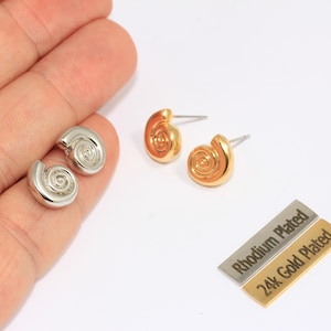 May include: Two pairs of stud earrings in the image. One pair is silver-colored, and the other is gold-colored. The earrings have a spiral design. Two small rectangular tags are also in the image, one labeled "Rhodium Plated" and the other "24k Gold Plated."
