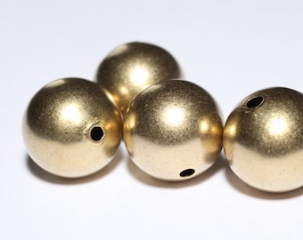 May include: Four round, metallic gold beads with a matte finish are arranged on a white surface. Each bead has a small, centered hole. These beads are suitable for jewelry making and crafting projects.