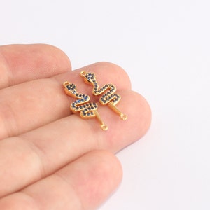 May include: Two gold-colored snake-shaped charms with blue gemstone accents. Each charm has a loop at the top and a post at the bottom for attaching to jewelry. The charms are displayed against a white background.