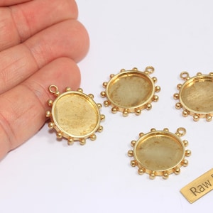 May include: Four brass pendant trays with a circular design and a small loop for attaching to a chain. Each tray has a raised edge with small, evenly spaced decorative balls. A small brass tag reads "Raw Brass."