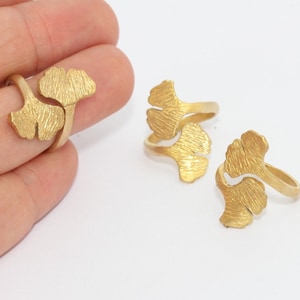 Può includere: Anelli color oro con un design a forma di foglia di ginkgo. Gli anelli hanno una superficie strutturata e sono mostrati su uno sfondo bianco. Questi anelli sono un gioiello unico.