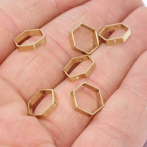 May include: Several small, gold-colored, hexagonal metal charms. Each charm has a hollow center and small holes for stringing. The charms are displayed against a neutral background.
