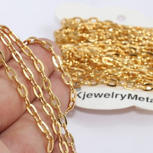 May include: Close-up of a gold-colored chain with oval links. The chain is in a roll and also laid out in a line. The chain is shiny and appears to be new. The text "KjewelryMetal" is visible on the packaging.