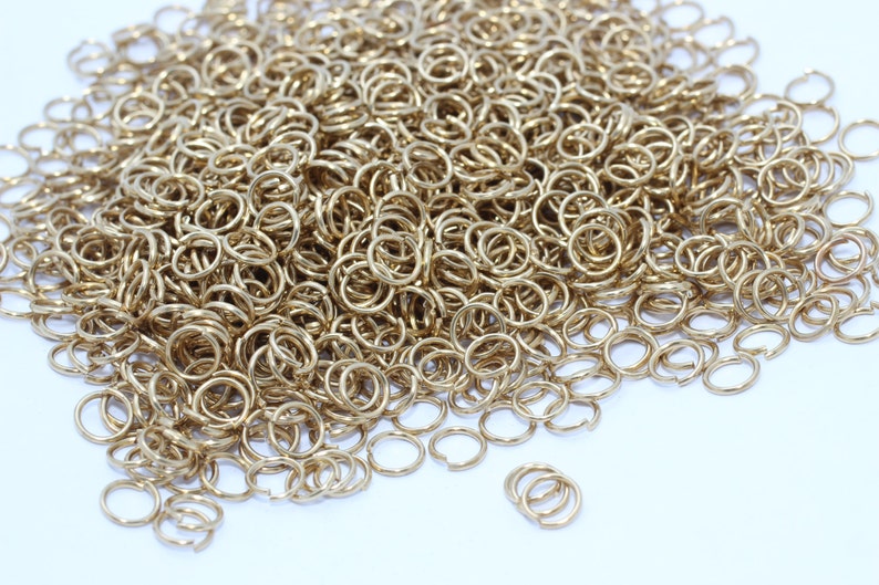 Puede incluir: Un mont&oacute;n de peque&ntilde;os anillos de salto de color dorado. Estos anillos abiertos se utilizan para la fabricaci&oacute;n de joyas y otras manualidades. Los anillos son redondos y tienen una peque&ntilde;a abertura para conectar otros componentes. Los anillos son de metal.