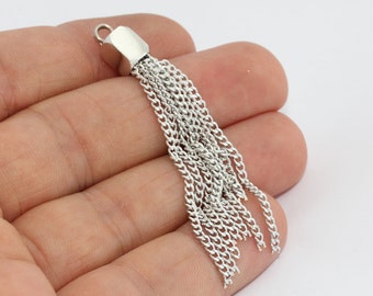 May include: Silver-colored tassel pendant with a geometric top and multiple chain strands. The pendant is designed for jewelry making or crafting. The tassel is held in a hand against a white background.