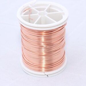 May include: A spool of copper wire, tightly wound and displayed against a white background. The wire is a warm, reddish-brown color, and the spool has a white plastic core. This item is suitable for jewelry making and crafting.