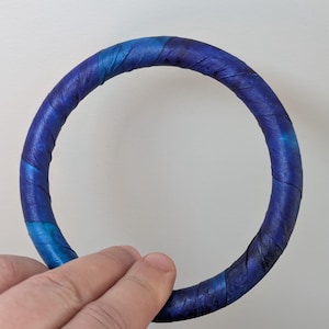 May include: A blue and teal ring made of fabric, with a swirling pattern.