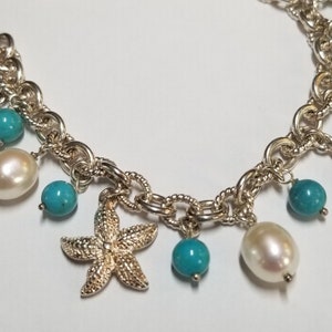 May include: A silver charm bracelet with turquoise and pearl beads. The charms include a starfish, a leaf, and a seahorse.