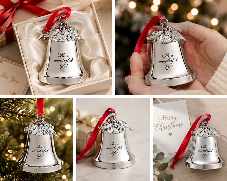 Pode incluir: Um ornamento de sino prateado com o texto gravado "It's a wonderful life!" e um topo decorativo com o ano "2026" e asas de anjo. Uma fita vermelha est&aacute; presa ao topo para pendurar, e o sino tem um acabamento polido.