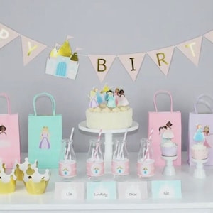 Toddler girls princess party decor in pastel and gold colors.  White table with a cake, gift bags and banner that reads happy birthday with a castle and pastel princess girls.