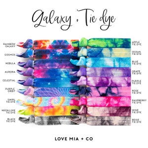 Pode incluir: Uma cole&ccedil;&atilde;o de el&aacute;sticos de cabelo coloridos com padr&otilde;es de gal&aacute;xia e tie-dye. Os el&aacute;sticos de cabelo apresentam v&aacute;rias cores e designs, incluindo gal&aacute;xia arco-&iacute;ris, cosmos, nebulosa e muito mais. O texto na imagem diz "Galaxy + Tie Dye" e "Love Mia + Co."