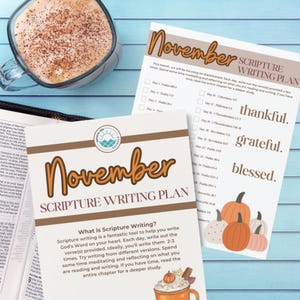 May include: Two printed November Scripture Writing Plan sheets with a coffee cup. The sheets have a brown and white design with text and a list of Bible verses. One sheet has the words "thankful, grateful, blessed" and pumpkin illustrations.