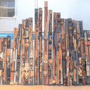 Puede incluir: Una escultura de pared hecha de varias piezas de madera, dispuestas en un patrón vertical. La escultura está compuesta por muchas formas y tamaños diferentes de madera, y las piezas están dispuestas de una manera que crea una sensación de movimiento y energía.