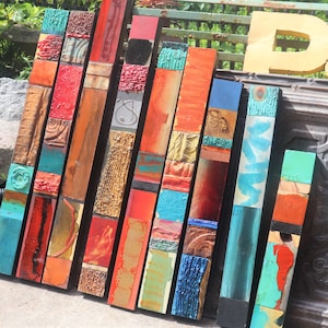 Puede incluir: Un conjunto de 10 paneles de madera verticales, cada uno con un diseño abstracto colorido diferente. Los paneles están hechos de madera y pintados con varios colores, incluyendo rojo, naranja, amarillo, verde, azul y turquesa. Los paneles están dispuestos en una fila, con el panel más alto a la izquierda y el panel más corto a la derecha.
