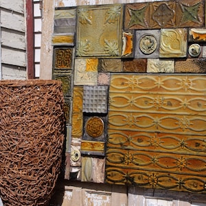 May include: A close-up of a wall covered in a mosaic of vintage, yellow and brown, ceramic tiles. The tiles are arranged in a random pattern and have a variety of designs. A brown wicker basket is in the foreground.