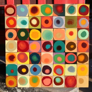 May include: A square artwork with a grid of 36 colorful squares, each containing a circle with a different color and pattern. The circles are arranged in a random pattern, creating a visually stimulating abstract design.