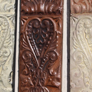 May include: Three decorative tiles with a raised heart design. The tiles are in shades of brown, beige, and white.