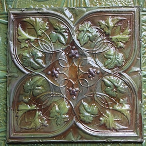 May include: A square tile with a green and brown glazed finish. The tile features a repeating pattern of stylized leaves and vines.