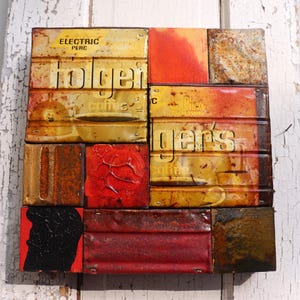 Puede incluir: Una obra de arte de técnica mixta compuesta por paneles metálicos reutilizados. La pieza presenta el texto "Holger's Coffee" y varias formas abstractas en tonos rojos, amarillos y marrones. La obra tiene una estética rústica e industrial.