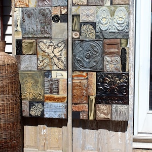 Könnte beinhalten: Zwei verwitterte Holztüren mit einem Mosaik aus alten Blechteilen in verschiedenen Farben und Mustern. Die Fliesen sind in einem zufälligen Muster angeordnet und erzeugen einen einzigartigen und rustikalen Look.