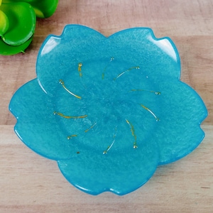 May include: A blue flower-shaped dish with gold accents. The dish is made of resin and has a glossy finish.