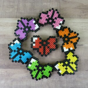 May include: A collection of eight colorful heart-shaped bead sprites, each with a different color pattern. The sprites are arranged in a circle around a red heart-shaped bead sprite.