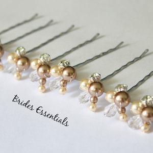May include: Six gold and ivory beaded hair pins with silver bobby pins. The pins are arranged in a row on a white surface. The text "Brides Essentials" is visible below the pins.