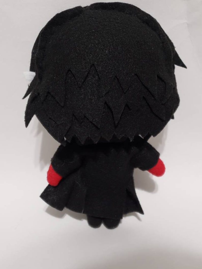 May include: Black and red plush toy of a character with spiky black hair and a black coat. The toy is facing away from the camera.