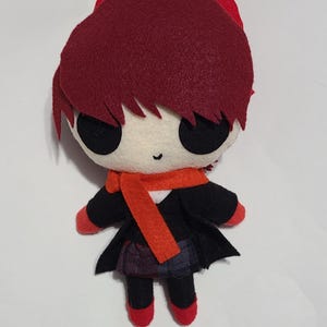 Puede incluir: Un juguete de peluche con pelo rojo, ojos negros y una bufanda roja. El juguete lleva un abrigo negro y una falda a cuadros. El juguete está hecho de fieltro y tiene un estilo lindo y de dibujos animados.