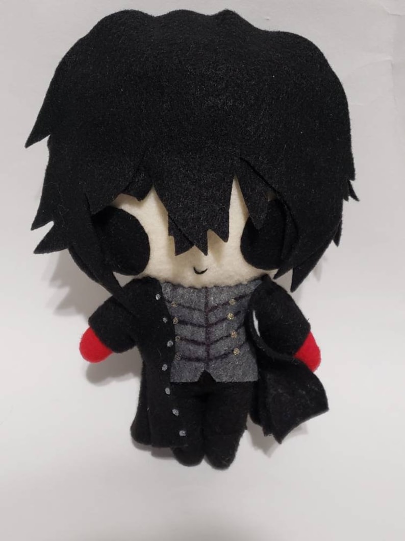 May include: A black and white plush toy of a character with black hair, a black coat, and red gloves. The toy has a simple, cartoonish style.