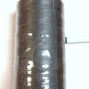 May include: A spool of gray thread wrapped in clear plastic with a blue plastic cap.