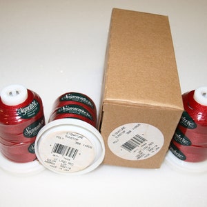 May include: Three spools of red thread labeled "Signature Sunstop Poly 360 Yards" and a brown box with the same label. The spools are in white plastic containers with a clear plastic top.