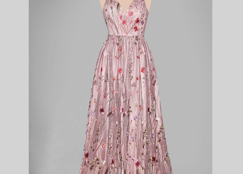 May include: A long, dusty rose maxi dress with a V-neckline and delicate floral embroidery. The dress has a fitted bodice and a flowing skirt.