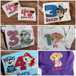 May include: A collection of white, light blue, and purple long-sleeve shirts featuring embroidered Paw Patrol character designs, large glittery numbers, and personalized names including Abigail, Emma, Georgie, Maddie, Ivy, Henry, and Scarlett.
