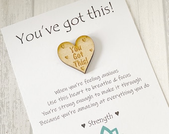 Könnte beinhalten: Eine weiße Karte mit dem Text "You've got this!" und einem Holzhäuschen mit dem Text "You Got This!" befestigt. Die Karte enthält auch den Text "When you're feeling anxious Use this heart to breathe & focus You're strong enough to make it through Because you're amazing at everything you do ♥ Strength ♥ Meaningful Charm www.meaningfulcharm.co.uk"