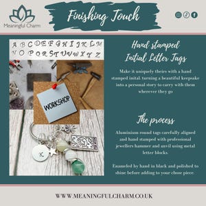 May include: A silver-toned keychain featuring a round metal tag stamped with the letter K, a small star charm, a four-leaf clover charm, a rectangular charm depicting a moon and stars, and three spherical beads in white and green shades.
