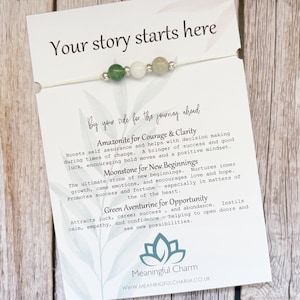 May include: A bracelet featuring three gemstone beads—green aventurine, moonstone, and amazonite—separated by small silver-toned metal spacers on a thin white cord. The bracelet is attached to a white display card with the text Your story starts here.