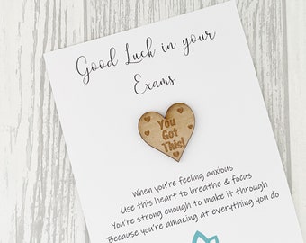 May include: A white card with the text "Good Luck in your Exams" and a wooden heart with the text "You Got This!" attached. The card has a message about using the heart to breathe and focus when feeling anxious.