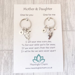 May include: A set of two silver keychains with a broken heart charm that says "Mother" and "Daughter". The keychains are on a white card with the text "I will wear mine every day to feel near while you're far away. If you wear yours from the start it will be like we were never apart." and the logo "Meaningful Charm" with the website address "www.meaningfulcharm.co.uk".