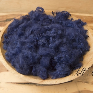 May include: A bowl filled with a large amount of dark blue wool roving. The wool is soft and fluffy, and it is perfect for felting or spinning.