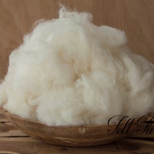 May include: A large pile of white wool fiber in a wooden bowl. The wool is soft and fluffy, and it is perfect for crafting.