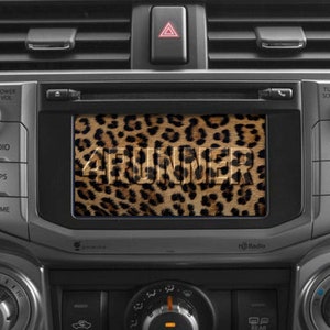 May include: A car dashboard with a screen displaying a leopard print background with the text "4RUNNER" in white letters.