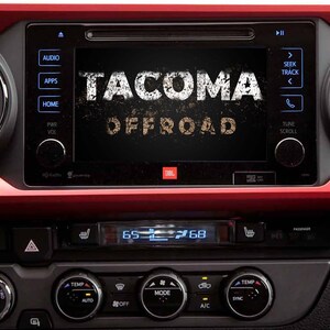 May include: A black dashboard with a touchscreen display showing the text "TACOMA OFFROAD". The display has buttons for audio, apps, home, power, and volume. The dashboard also has a digital display showing the temperature and a row of buttons for climate control.