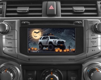 May include: A white SUV with a black roof rack drives through a spooky Halloween scene with a full moon, bats, and jack-o'-lanterns. The scene is displayed on a car's infotainment system.