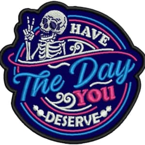May include: Embroidered patch with a dark blue background and a black border. The patch features a white skeleton giving a peace sign, with the text "Have The Day You Deserve" in white, pink, and blue.