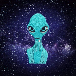 May include: Embroidered patch featuring a teal alien with large black eyes and a small mouth. The alien is set against a dark blue background with white star-like dots, creating a space-themed design.