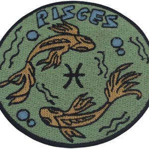 May include: Circular patch featuring the Pisces zodiac symbol. The design includes two stylized fish in shades of brown, swimming around the Pisces symbol. The word "PISCES" is arched across the top in blue letters, set against a green background.